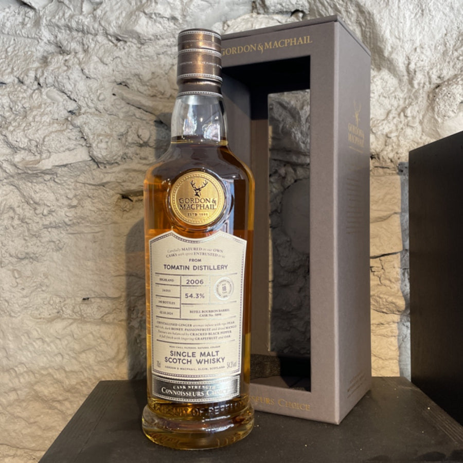 Bottle of Gordon & MacPhail single malt Scotch whisky with packaging on a stone surface.