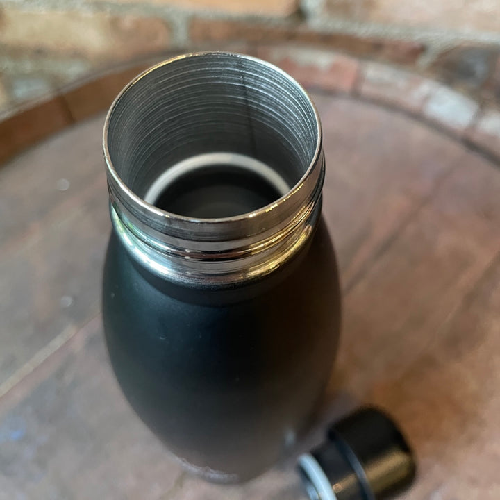 Black insulated bottle with metal cap on a wooden surface